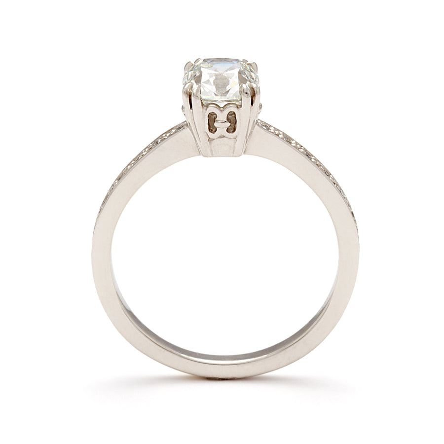 Side view of a solitaire ring with a knife edge white diamond with white diamond pave on either side set in white gold.