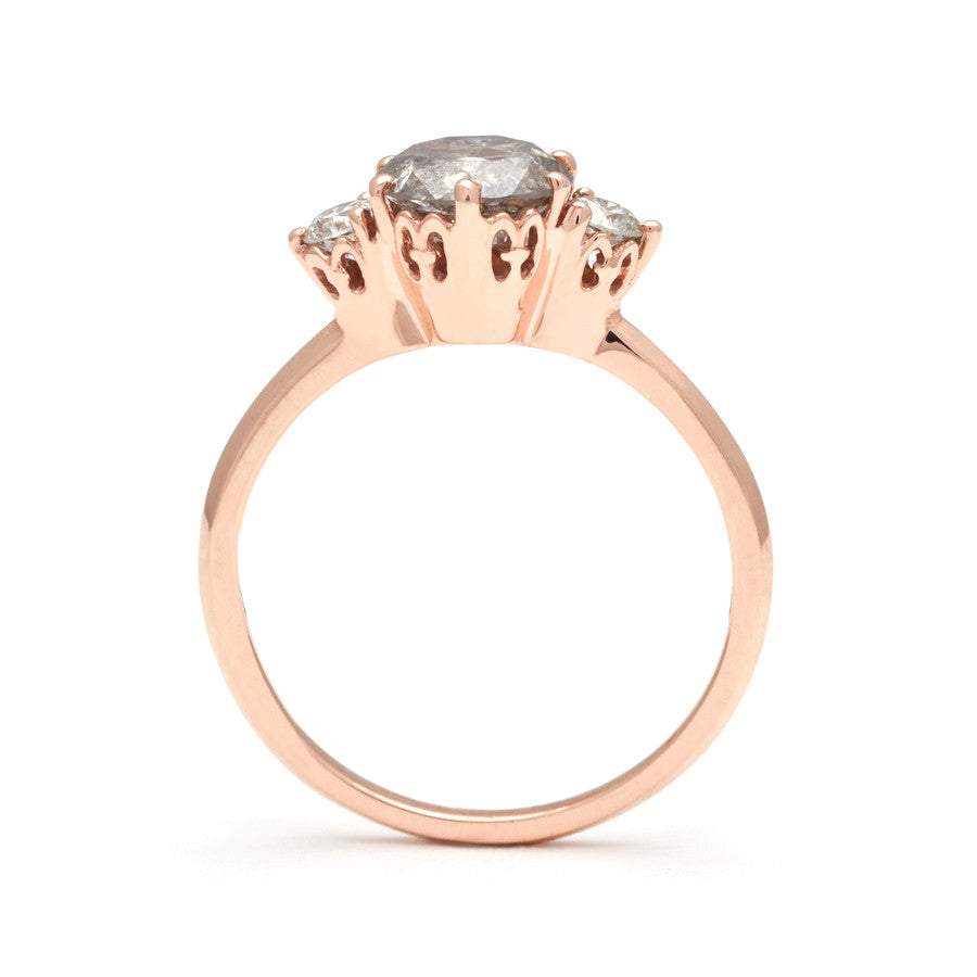 Side view of a three stone engagement ring with a round shape grey diamond center stone with two white diamond round side stones set in a rose gold band., Rose Gold
