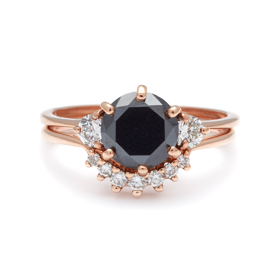 A three stone engagement ring with a round shape black diamond center stone with two white diamond round side stones set in rose gold stacked above a small 7 white diamond curve band in rose gold., White Gold, Rose Gold, Yellow Gold