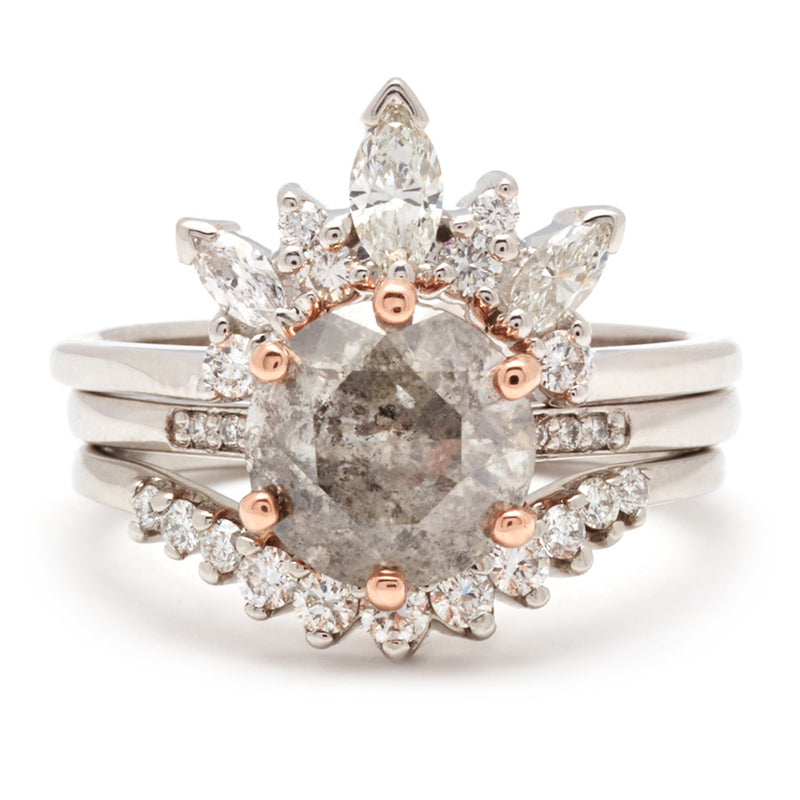 A solitaire ring with a round grey diamond with white diamond pave on either side set in white gold inbetween a marquise white diamond band and an 11 white diamond curve band.