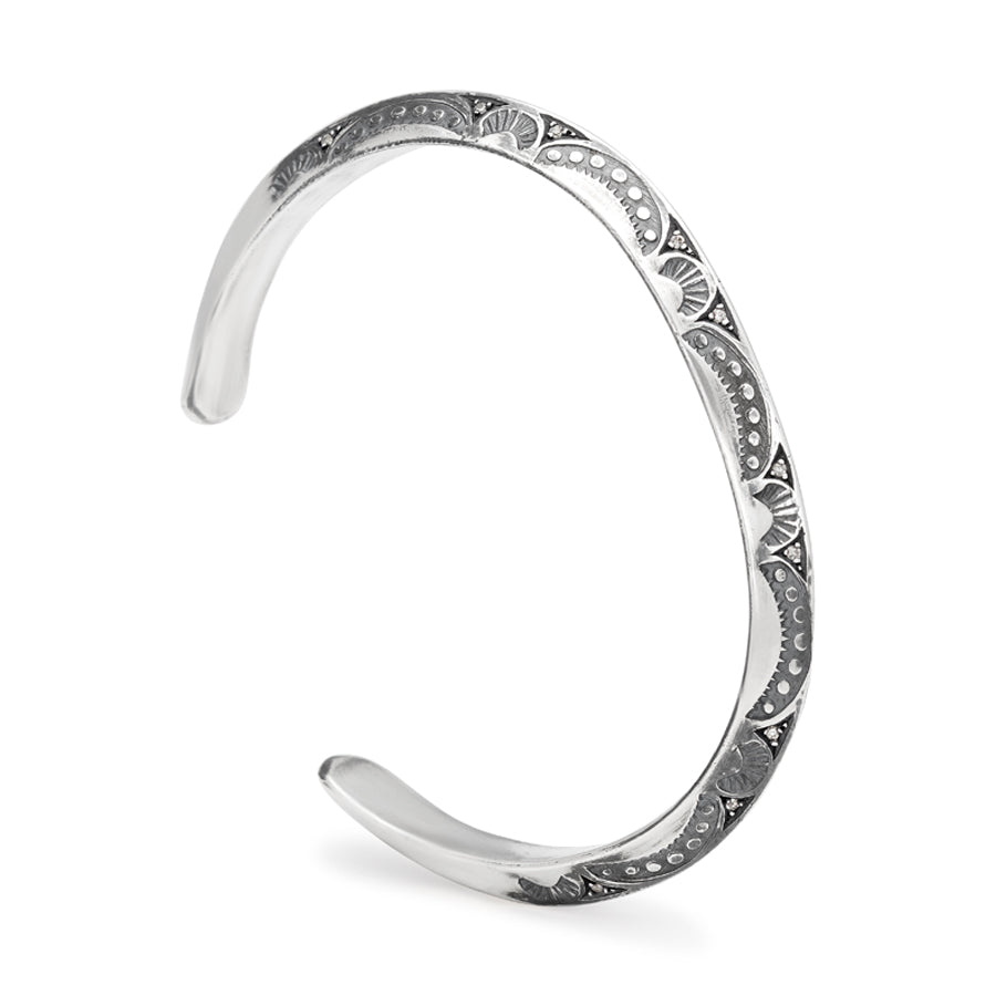 Angled view of a bracelet cuff with moon shaped engravings set in sterling silver.