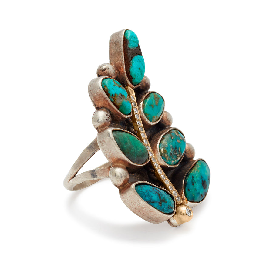 Angled view of a leaf shaped, one of a kind ring with turquoise stones and white diamond pave set in yellow and white gold.