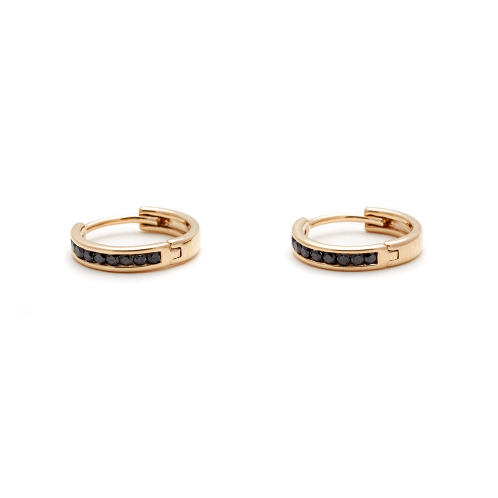A side view of a pair of hoops with a line of black diamonds set in yellow gold.