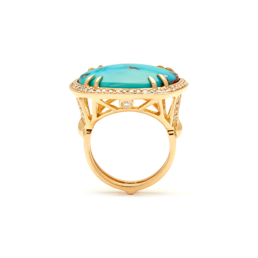 Side view of an oval shape turquoise center stone with double claw prongs surrounded by a white diamond pave halo set in yellow gold.