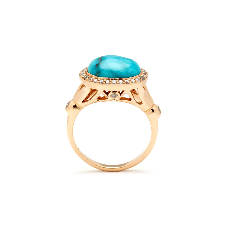 Side view of an engagement ring with an oval shape turquoise center stone surrounded by a champagne diamond pave halo with two white diamond accent side stones set in yellow gold.