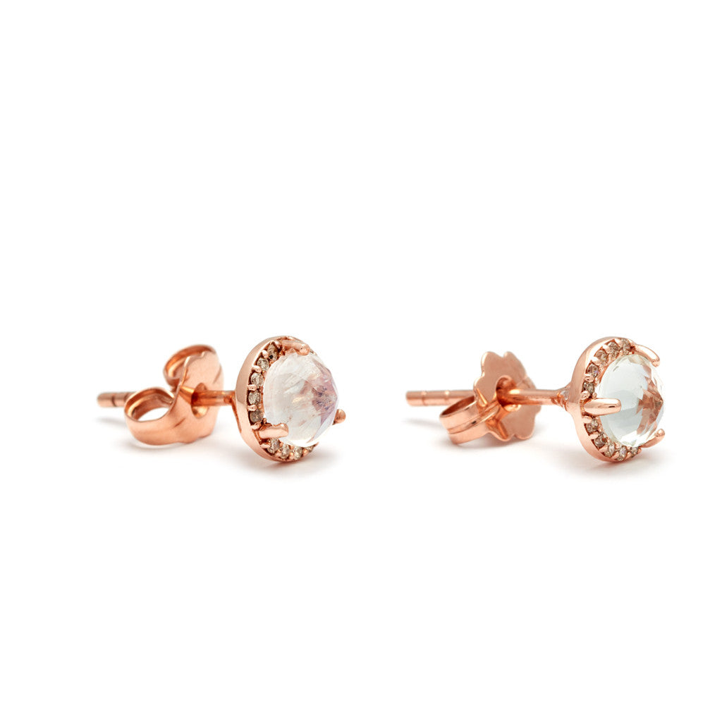 Angled view of a pair of medium rainbow moonstone center stone earrings with a halo of champagne diamond set in rose gold.