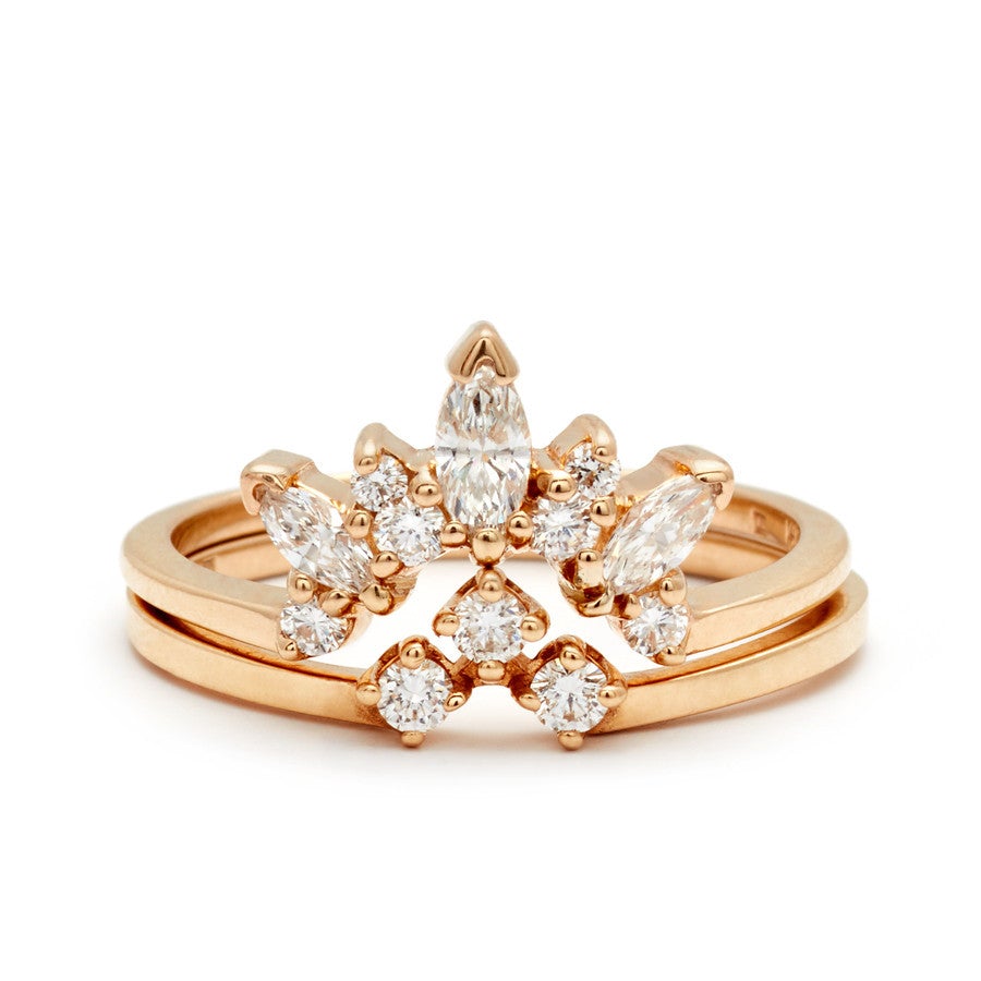 A multiple marquise tiara band with white diamonds stacked above a three round white diamond set in an arrow shape both set in yellow gold.