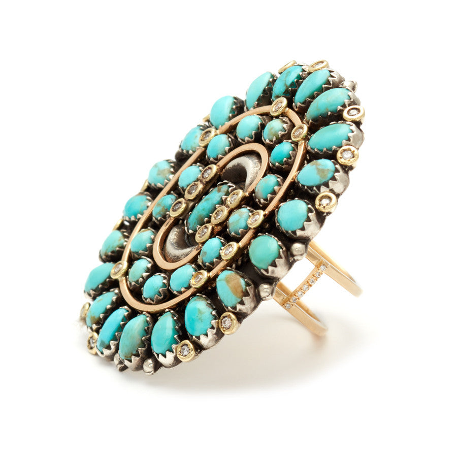 Angled view of an oval Turquoise concho harness ring set in yellow gold.
