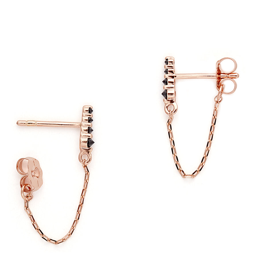 Side view of a pair of earrings with four black diamonds with a chain connecting to the ear back set in rose gold., Rose Gold