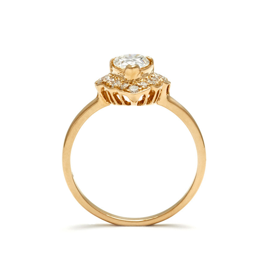 A side view of a pear shaped ring white diamond set in a halo of white diamonds and in yellow gold.