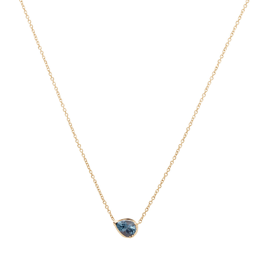 Zoomed out view of a necklace with a pear pendant with a grey spinel set in yellow gold with a yellow gold chain.