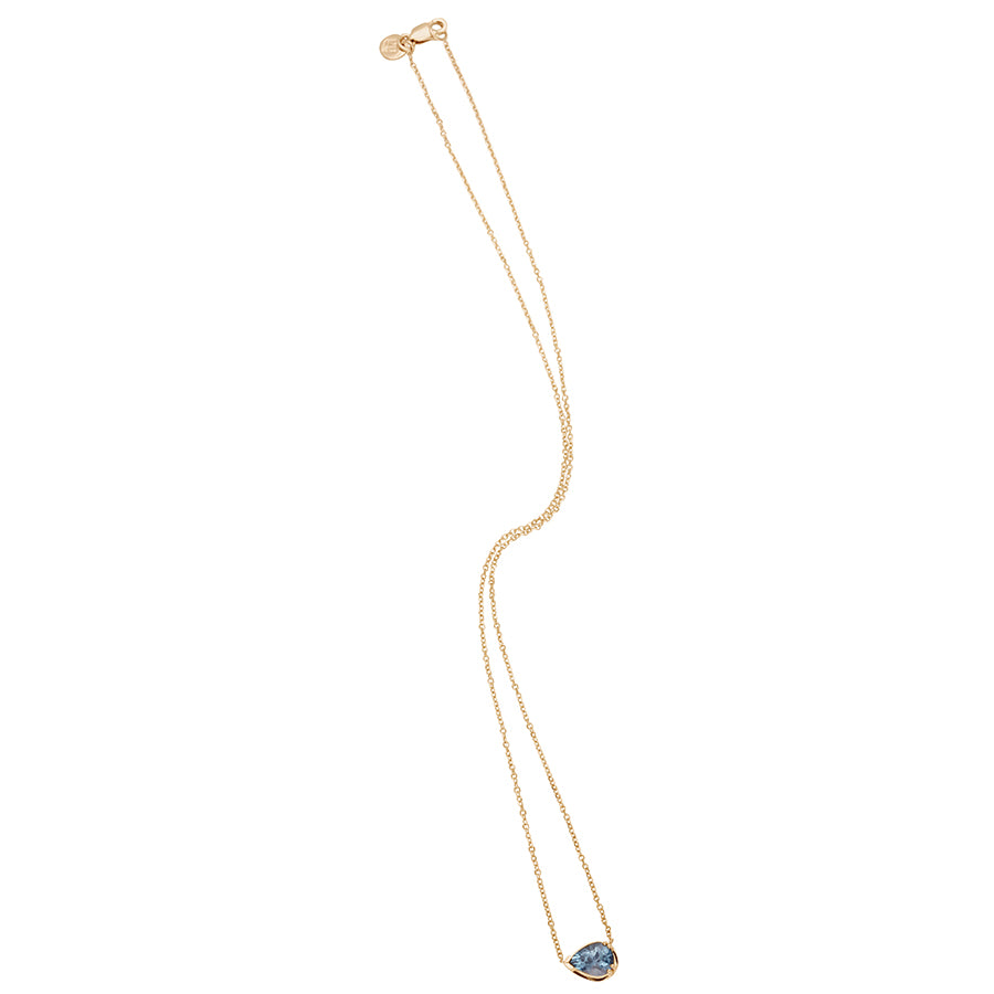 Zoomed out view of a necklace with a pear pendant with a grey spinel set in yellow gold with a yellow gold chain.