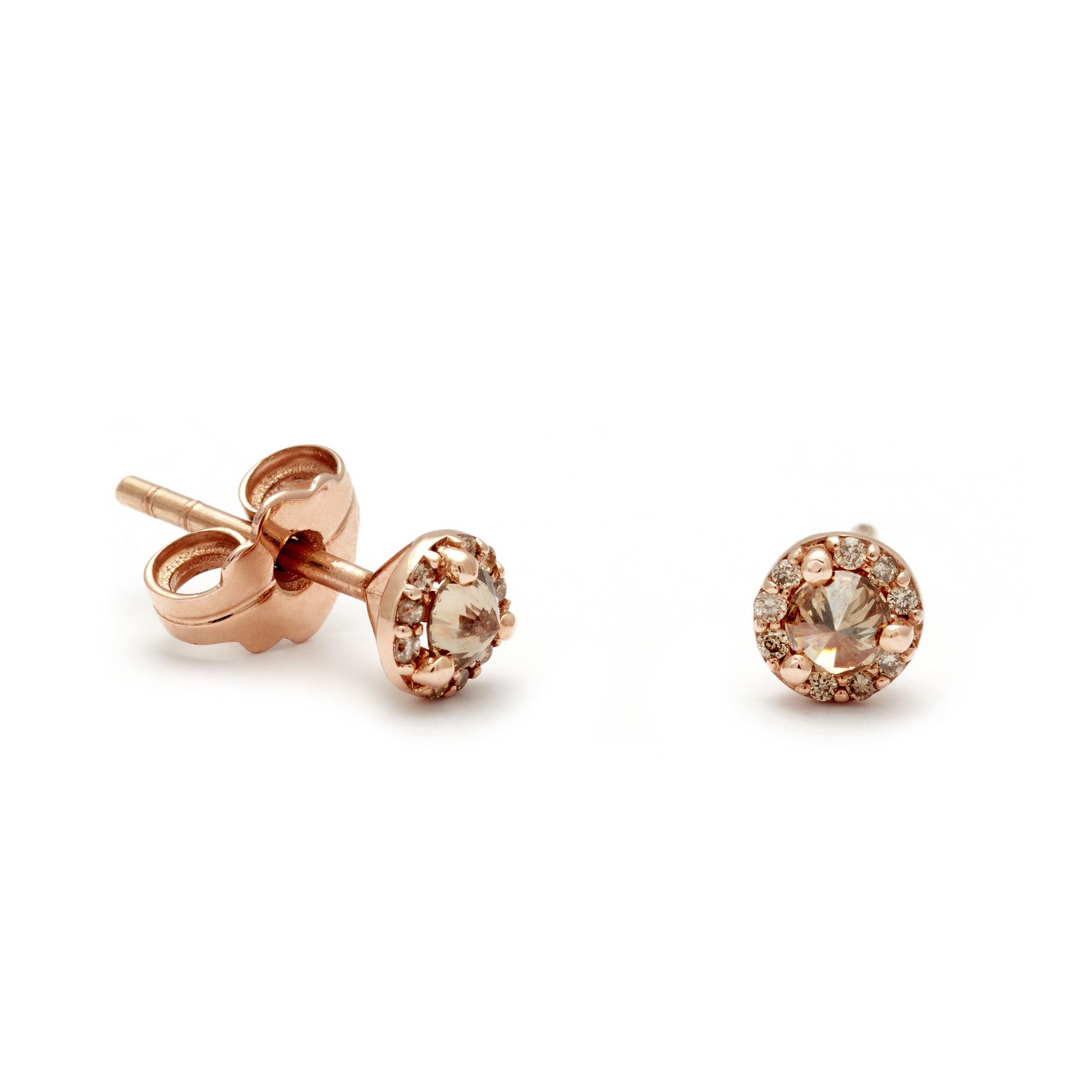 A pair of tiny champagne diamond center stone earrings with a halo of champagne diamond set in rose gold one earring angled.