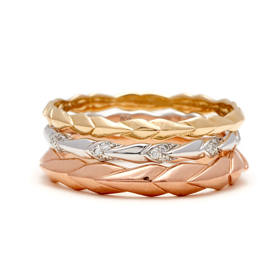 3 straight bands with leaf like designs, one in yellow, white, and rose gold in three different millimeters and one with white diamond accent stones.