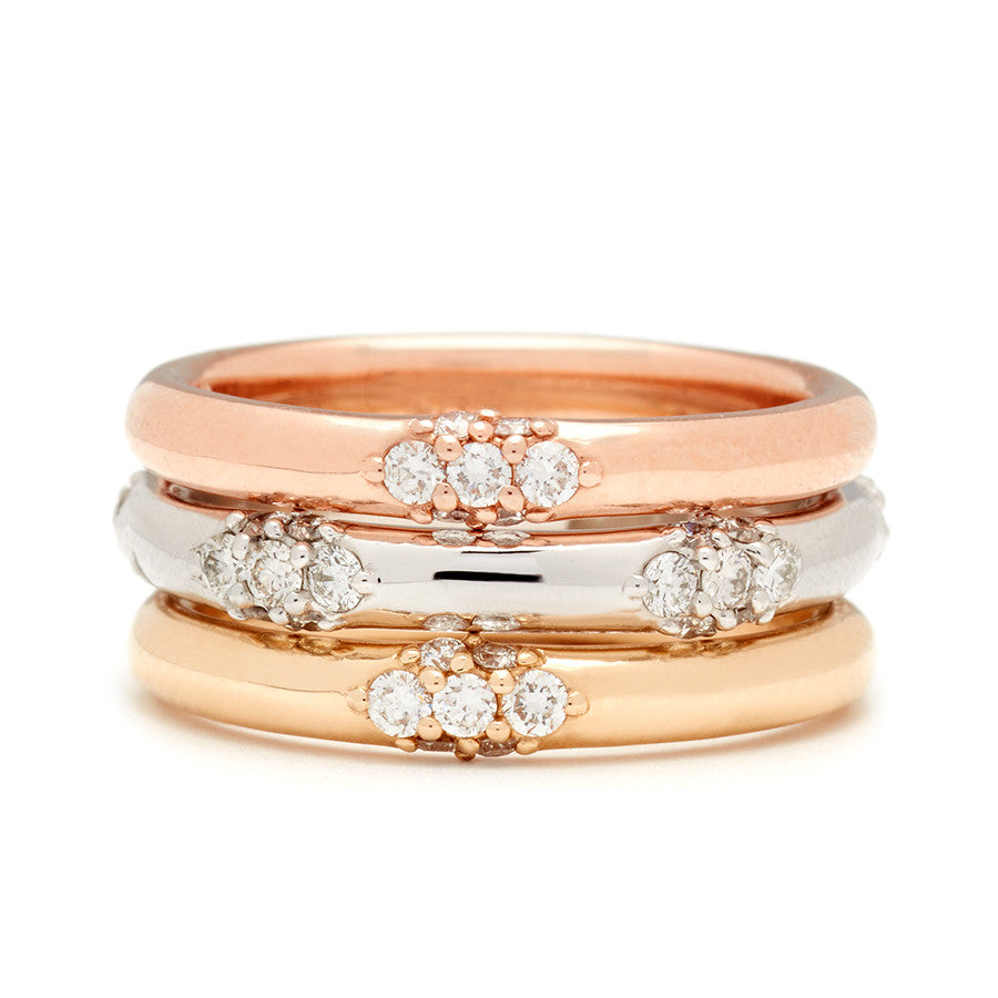 Three straight bands one with five clusters of white diamond accent stones stacked between two single cluster white diamond bands.