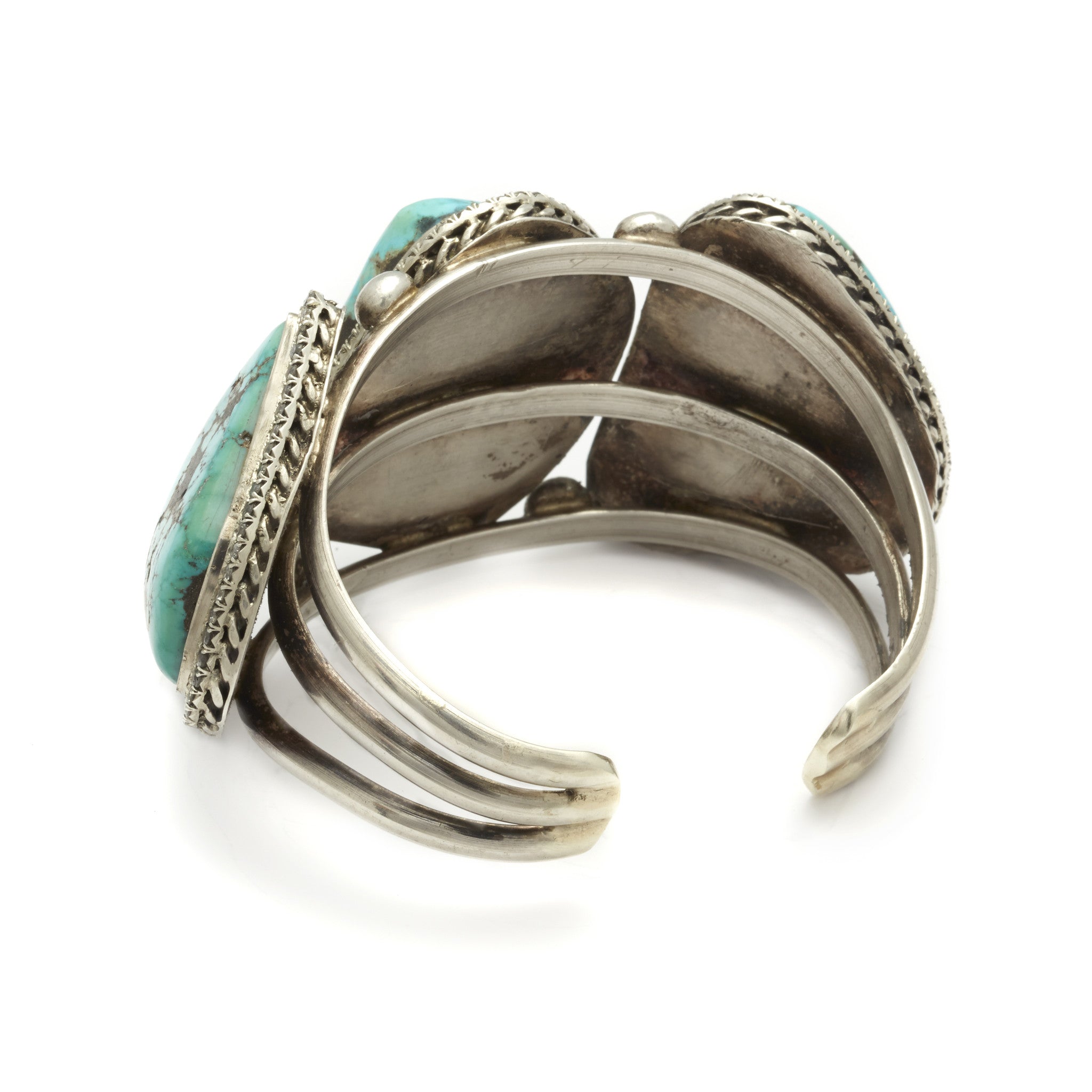 Upside down view of a three turquoise stones set in sterling silver with a halo of white diamond set in a cuff.