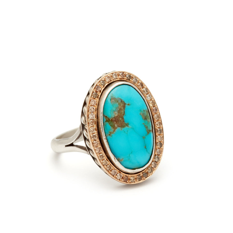 Angled view of an engagement ring with an oval shape turquoise center stone surrounded by a champagne diamond pave halo set in yellow and white gold.