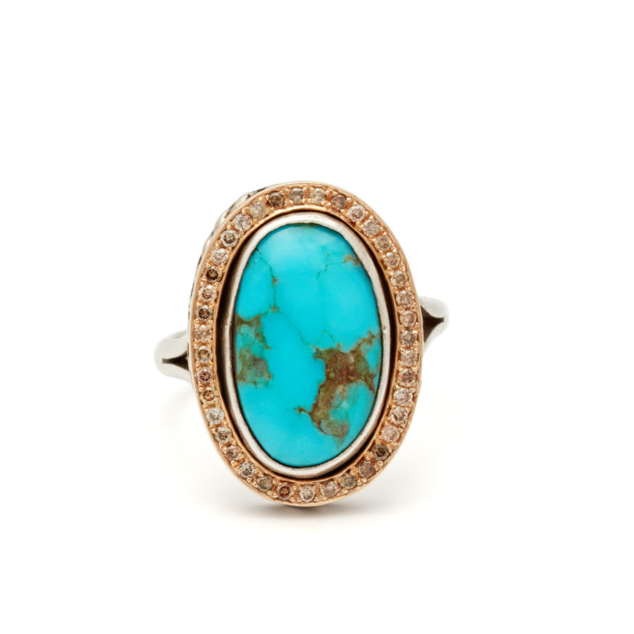 An engagement ring with an oval shape turquoise center stone surrounded by a champagne diamond pave halo set in yellow and white gold.