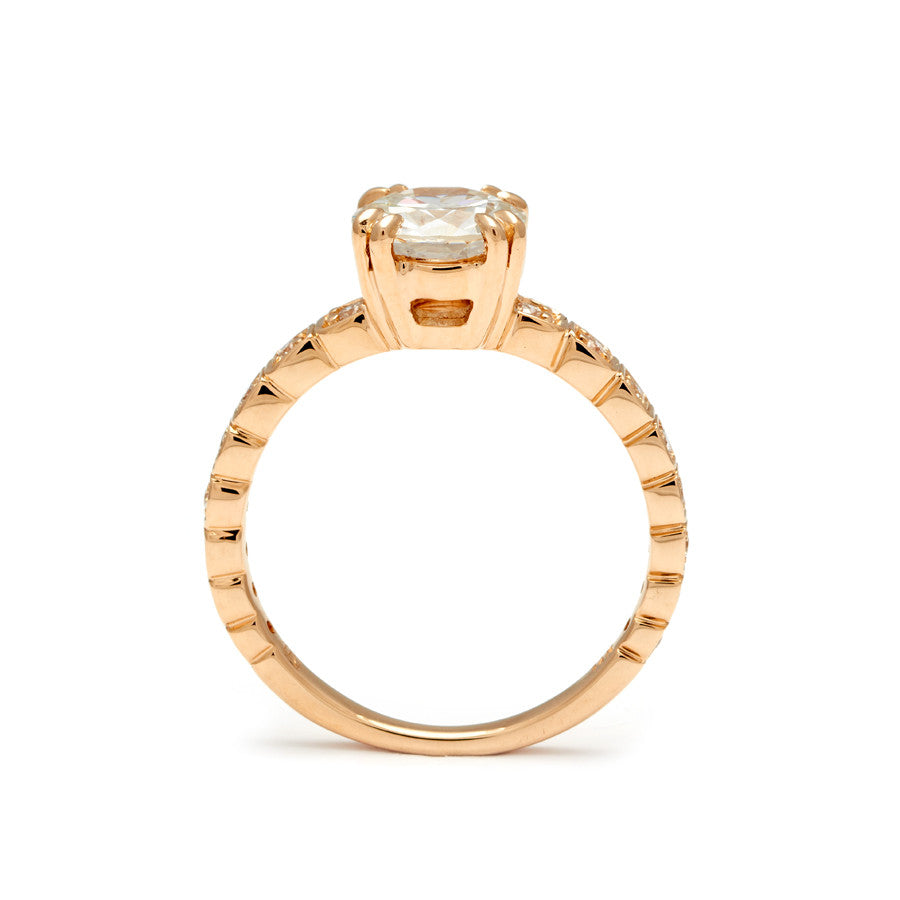 Side view of a solitaire ring with a euro cut white diamond with white diamond pave around the band set in yellow gold.