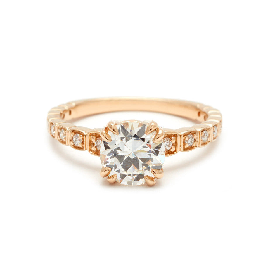 A solitaire ring with a euro cut white diamond with white diamond pave around the band set in yellow gold.